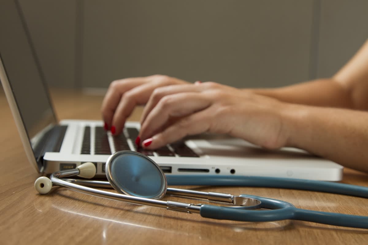 Arzt hält die Hand einer Patientin im Krankenhausbett — Erwerbsminderungsrente bei Krebs